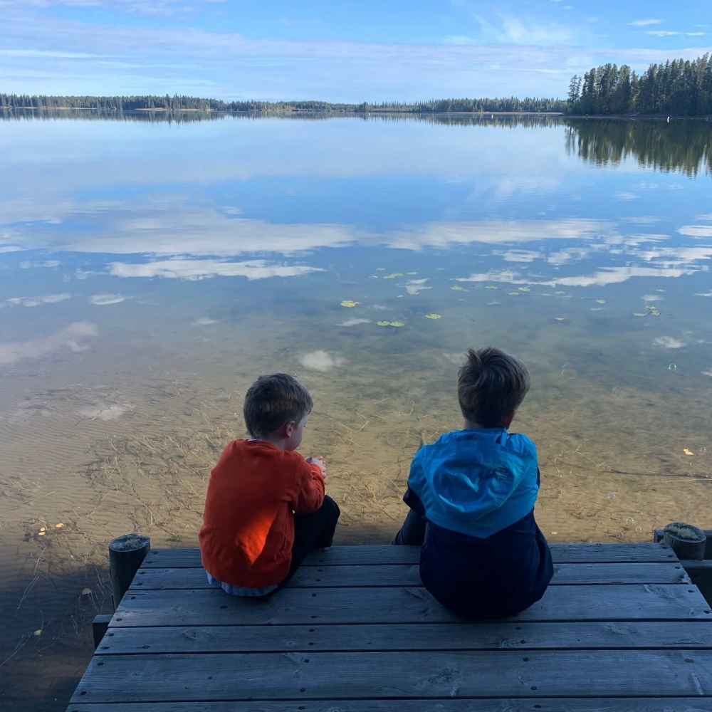 Two little boys sitting on a dock looking out over Crimson Lake
